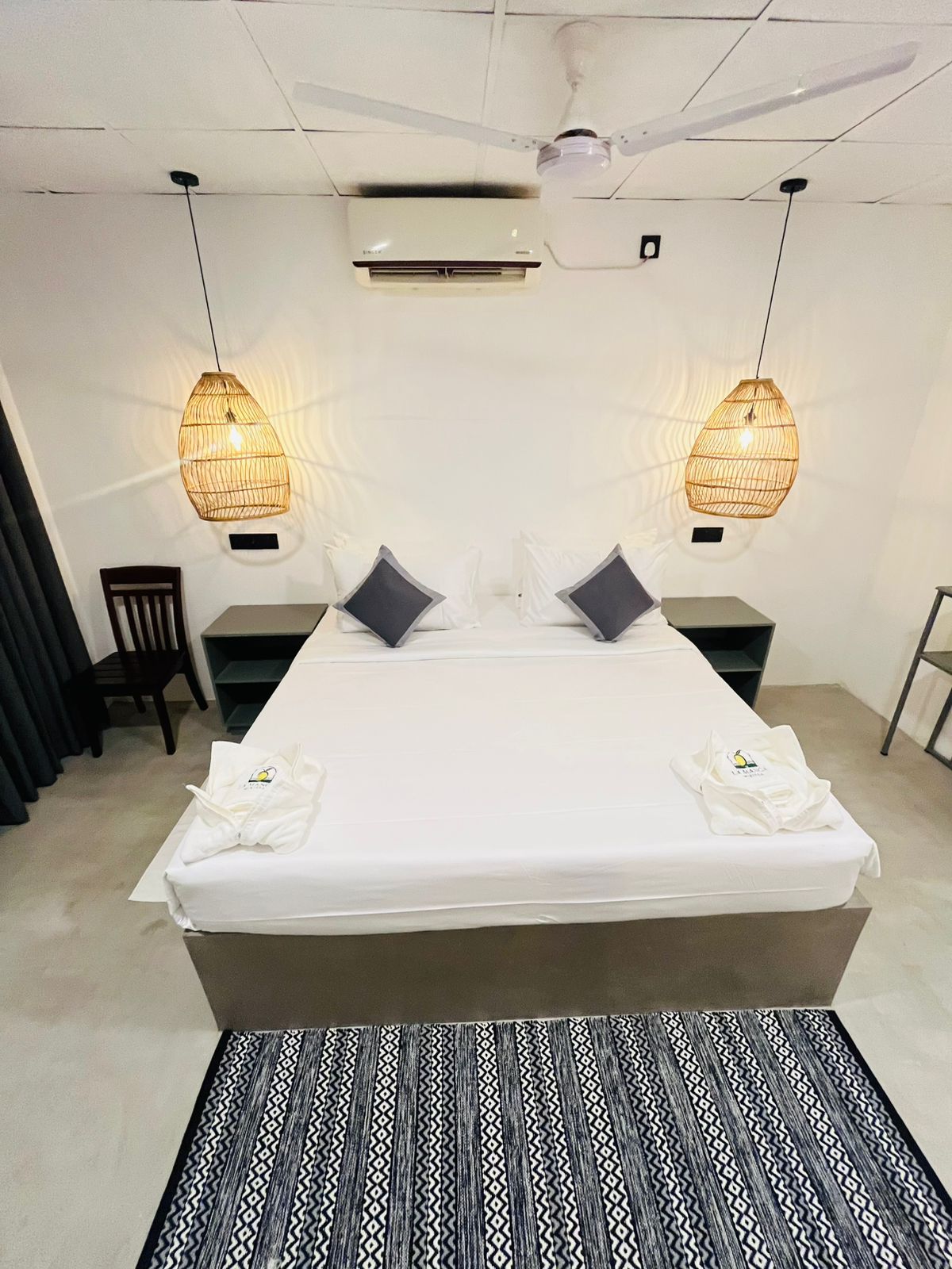Bright double bedroom at LÁ MANGÁ with woven rattan pendant lights, ceiling fan and air conditioning