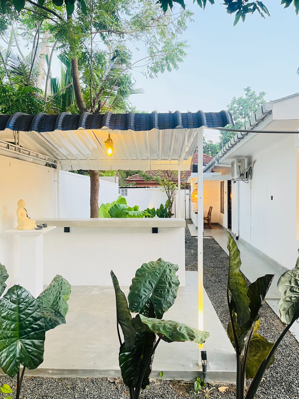 Planted garden courtyard with shaded seating and a paved walkway between the rooms