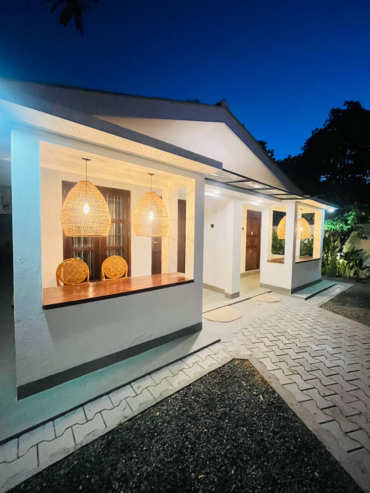 LÁ MANGÁ guest house at blue hour with warmly lit windows and a paved driveway