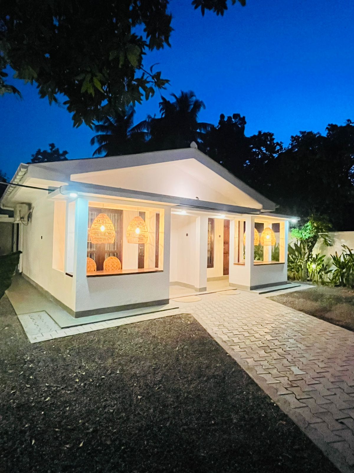 Front of the property lit up at night, showing the private entrances to each room