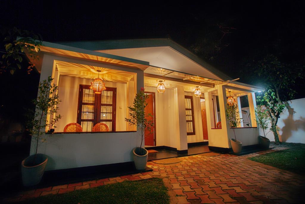 Long lit veranda running along the front of LÁ MANGÁ with potted plants and brick paving
