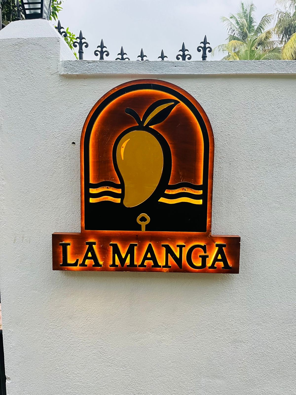 LÁ MANGÁ mango logo sign mounted on the whitewashed exterior wall