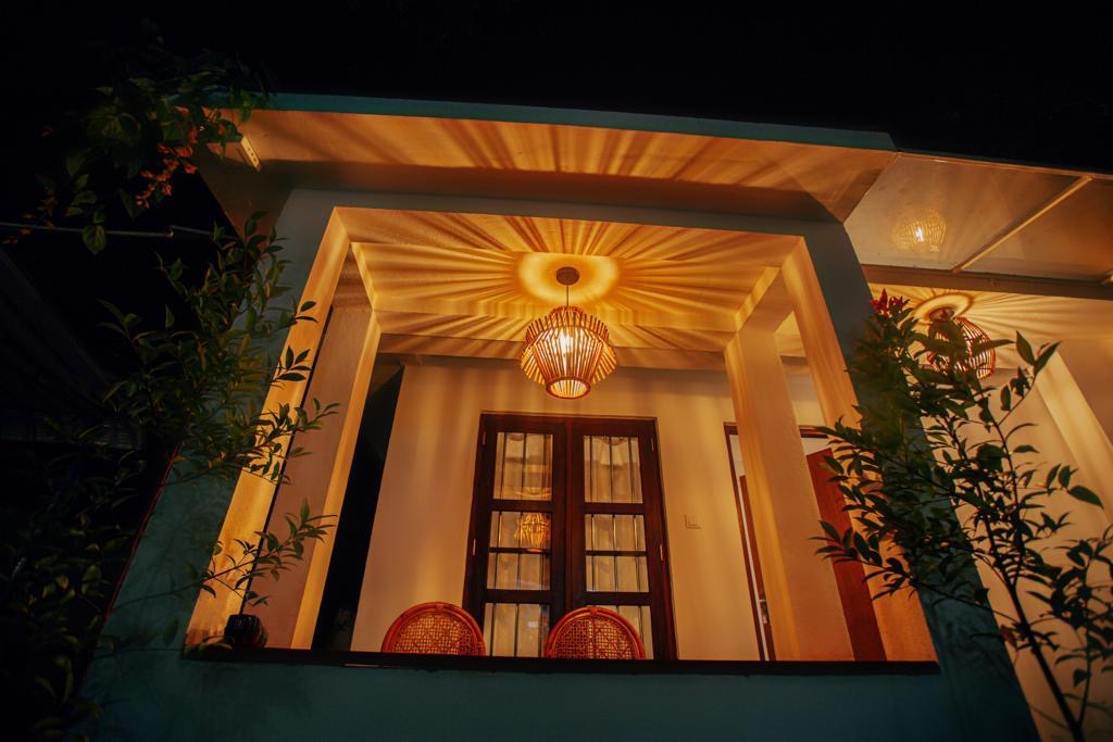 Covered veranda seating area glowing under warm light beside an arched window